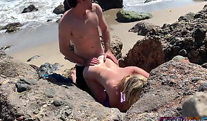 Voluptuous fair-haired sunbathing nude on shore copulates passerby